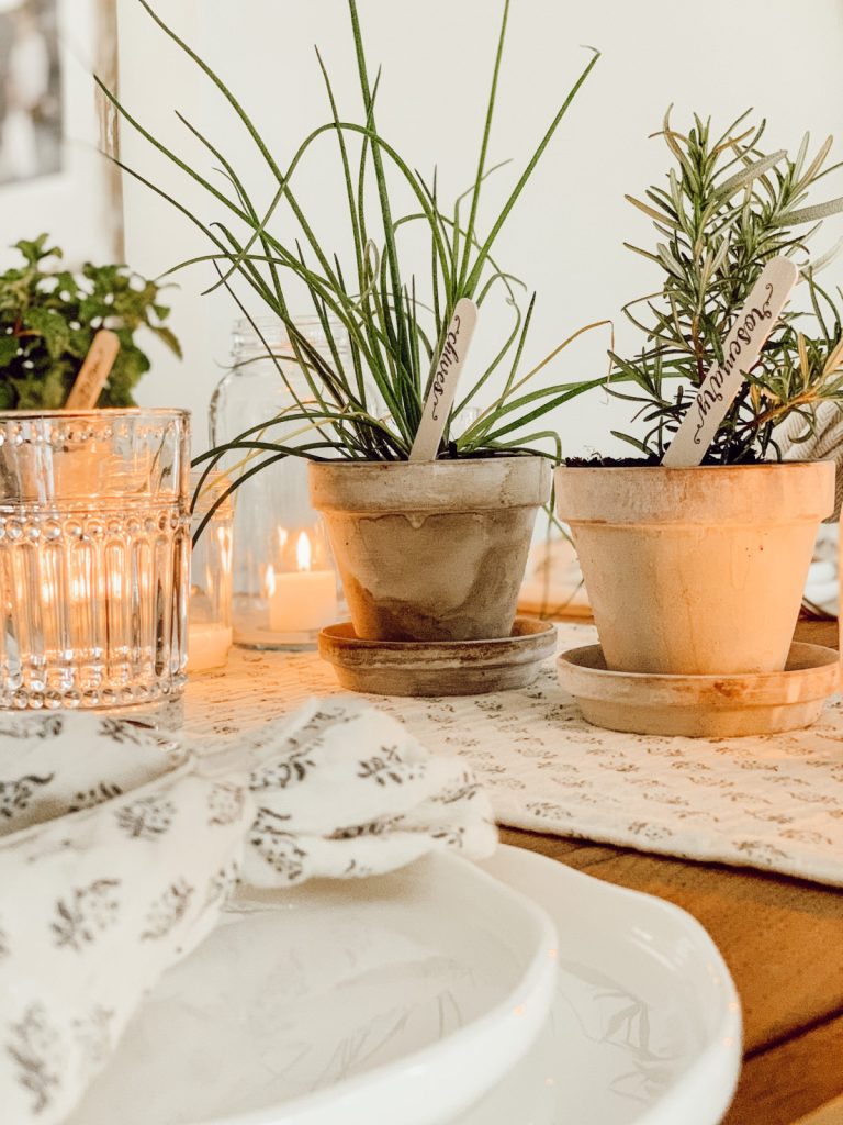 Mother's Day table decorations include fresh herbs, candlelight, and linen napkins.