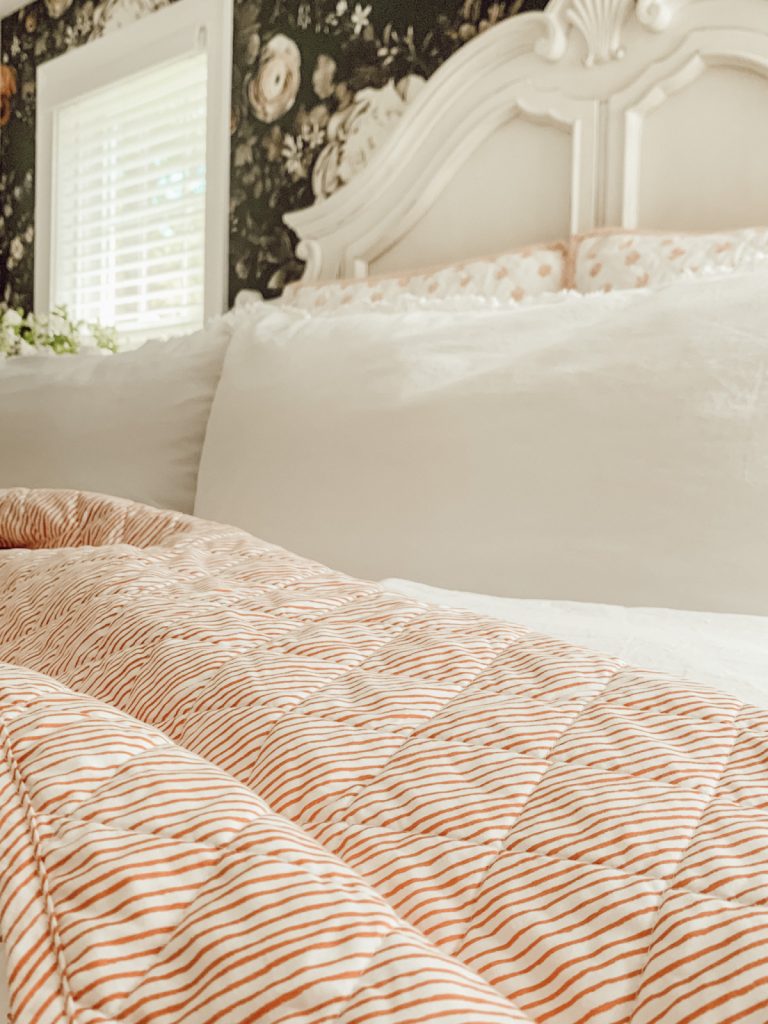 Farmhouse bedding with floral wallpaper in a cottage farmhouse home.