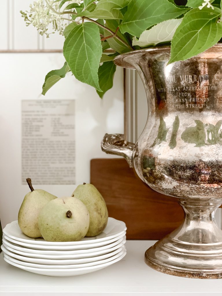 Silver urn & group of pears on open kitchen shelving.