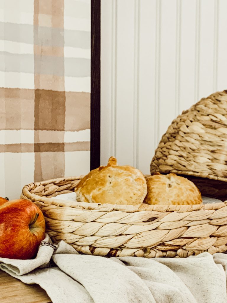 Mini apple pies on display in a woven cloche with a kitchen towel.