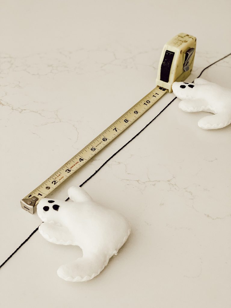 Supplies for making a Halloween garland include a tape measure, scissors, and hot glue.