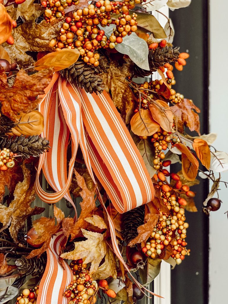 An autumn wreath hung on the front door with seasonal ribbon.