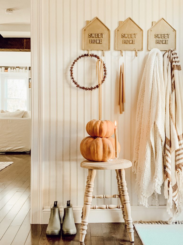 Cottage farmhouse entryway with pumpkins, blankets, and seasonal accents.