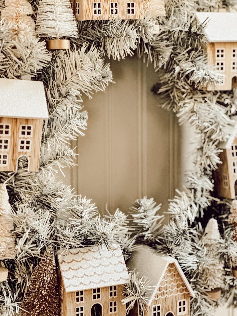 DIY Christmas wreath for the holidays with wooden houses and little bottle brush trees. 
