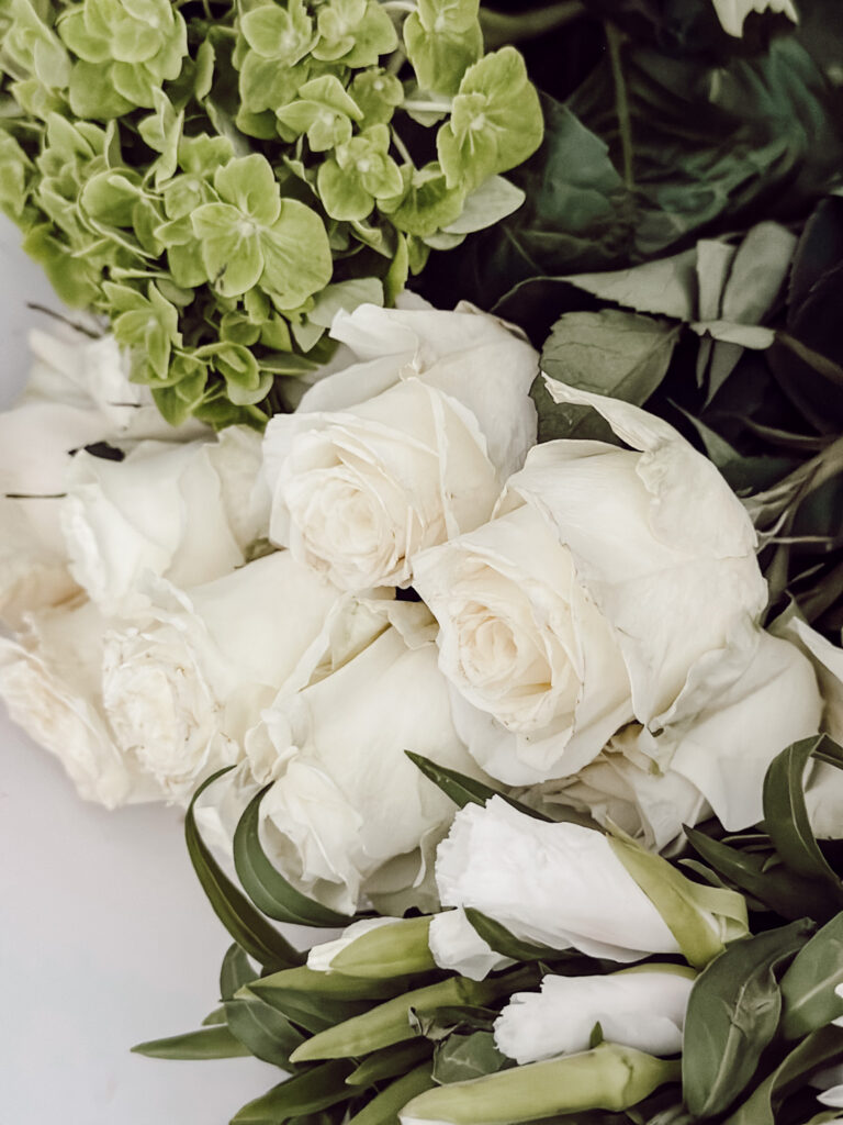 Fresh flowers include white roses, green hydrangeas, and eucalyptus for a tureen arrangement.