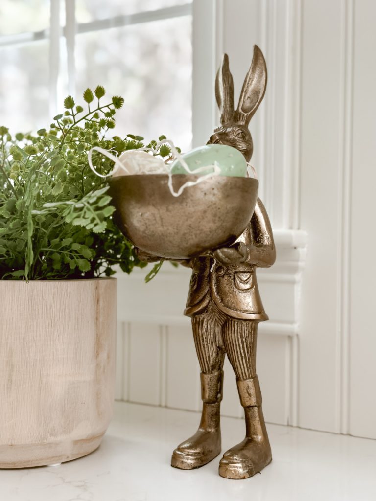 Bronze bunny holding eggs in a cozy farmhouse kitchen.
