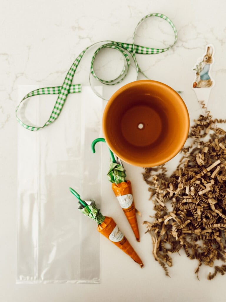 You'll need cellophane bags, chocolate carrots, brown shredded paper, terracotta flower pots, gingham ribbon, and a Peter Rabbit cutout to make this spring DIY.