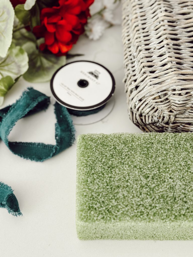 Supplies for a summer door basket with red geraniums & blue ribbon.