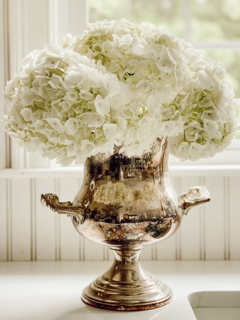 Hydrangea blooms in a vintage silver urn for a fresh, beautiful centerpiece.
