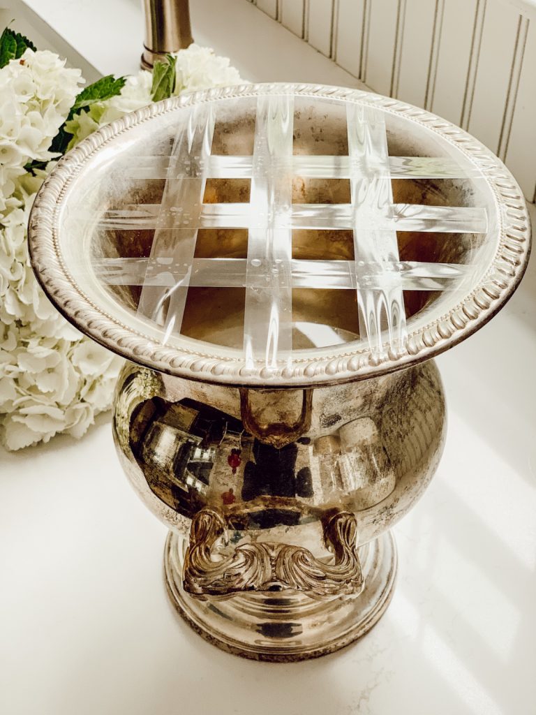 Silver vintage urn with scotch tape along the top to create a grid for adding the hydrangea stems easily to the vessel. 