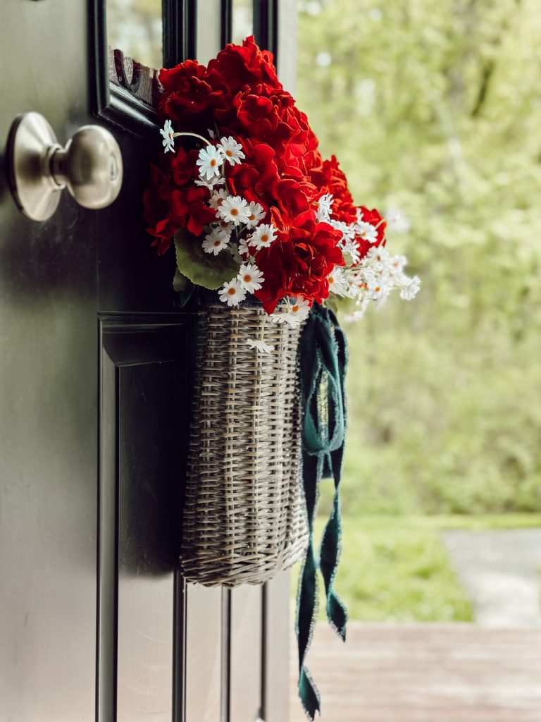 Add summer decor to your front door with seasonal flowers and ribbon.