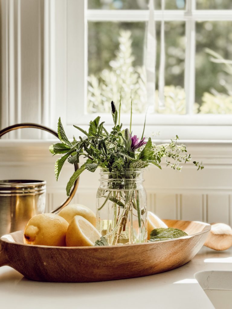 Summer kitchen with lemons and herbs in a wooden bowl.