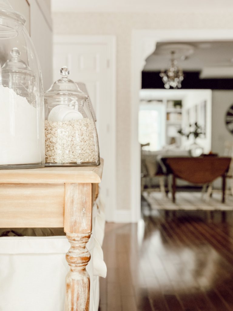 Farmhouse kitchen decor with glass canisters on wooden table.