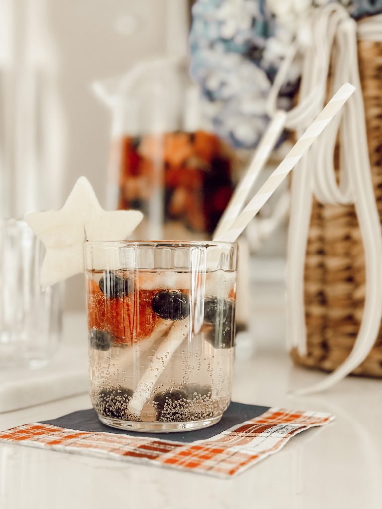 Glass of refreshing summer sangria with a pitcher of sangria behind it.