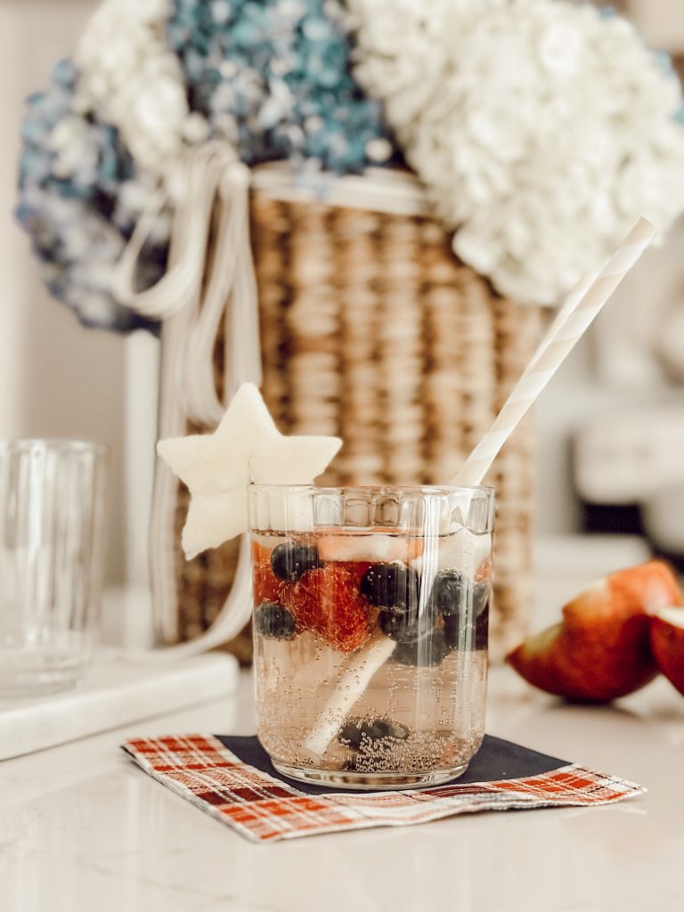 Refreshing summer cocktail wine sangria in a glass cup with star shaped fruit for festive flair.