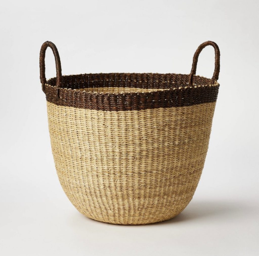 Brown handled storage basket that can be used to hold blankets.