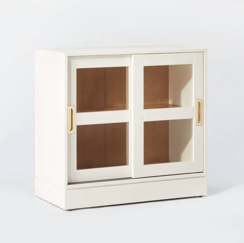 Cream end table with sliding doors for storage.