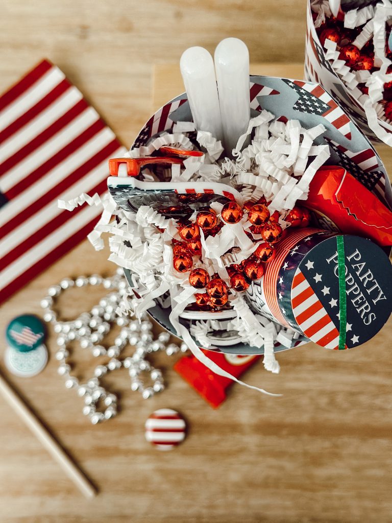 You'll need scrapbook paper, tape, glow sticks, mini flags, sunglasses, necklaces, buttons, and candy.