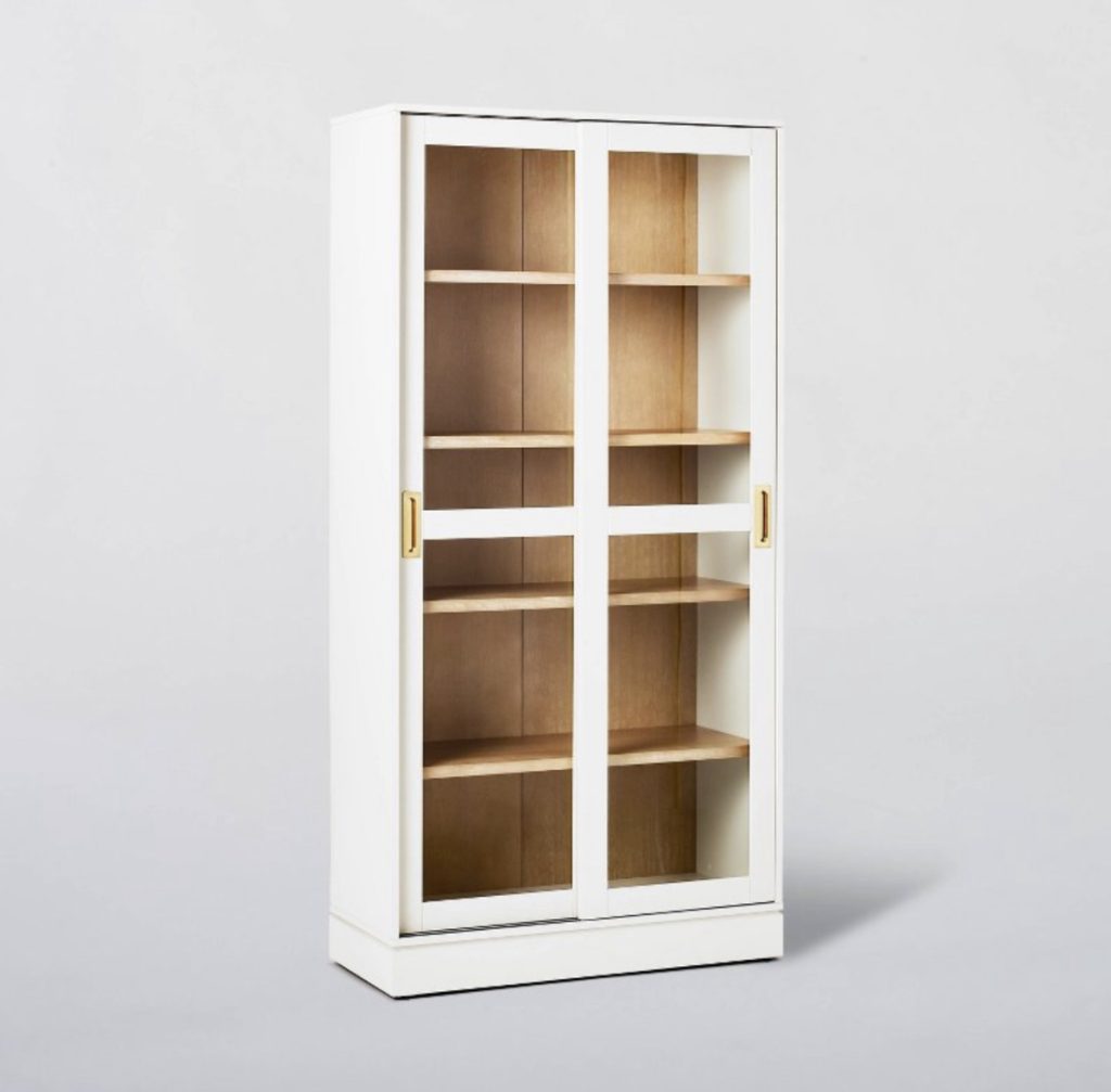 White cabinet with wood shelves for displaying home decor.