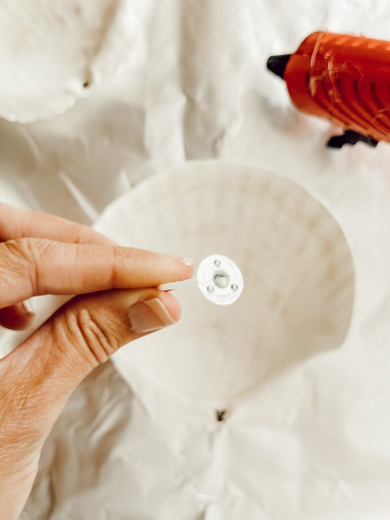 Attaching the candle wicks to the inside of the shells with hot glue.