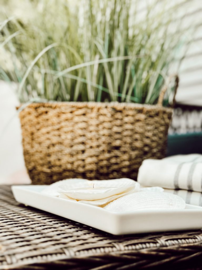 Coastal decor with shell candles, seagrass, and beach towels.
