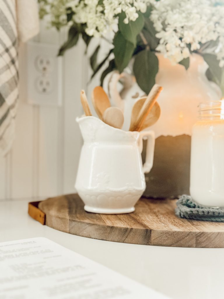 Functional kitchen decor with a small creamer filled with wooden spoons.