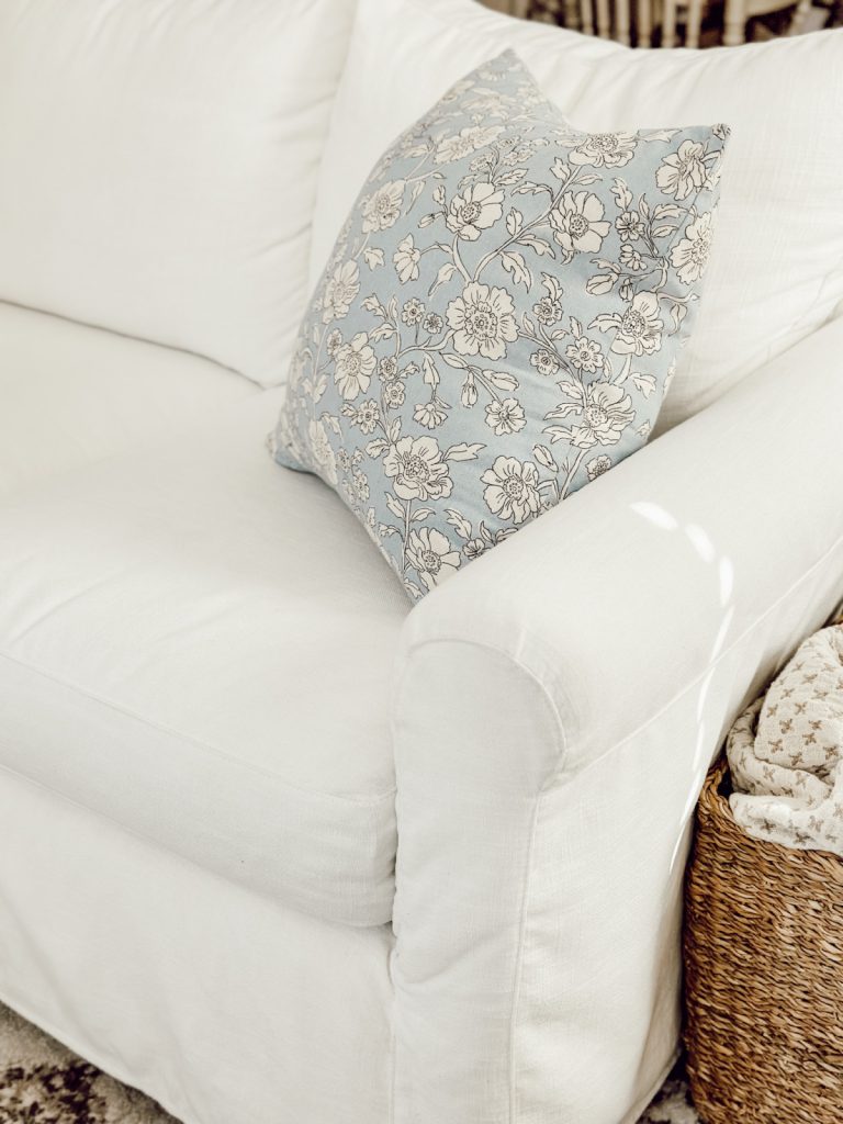 White couch with a splash of color from a blue accent pillow.