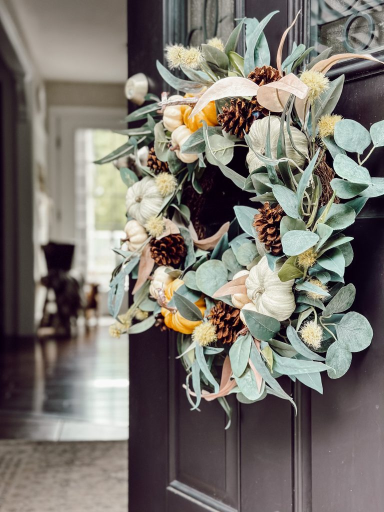 DIY pumpkin wreath for fall home decor with pumpkins and pinecones.