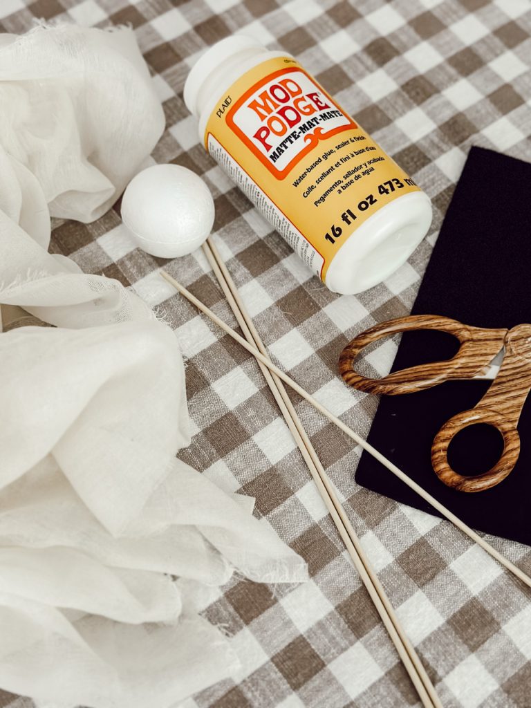 Supplies for Halloween craft that includes cheesecloth, Mod Podge, skewers, and more.