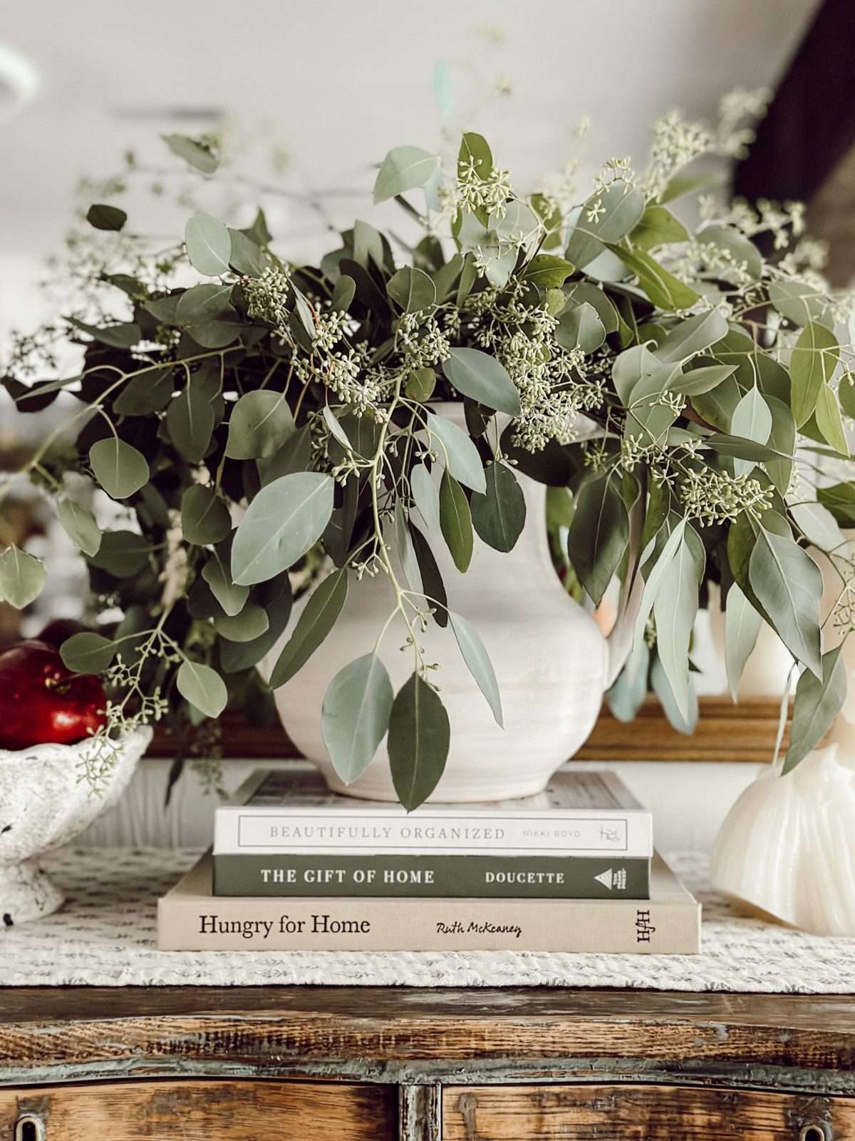 Minimalist fall decor with fresh greenery and a bowl of apples.