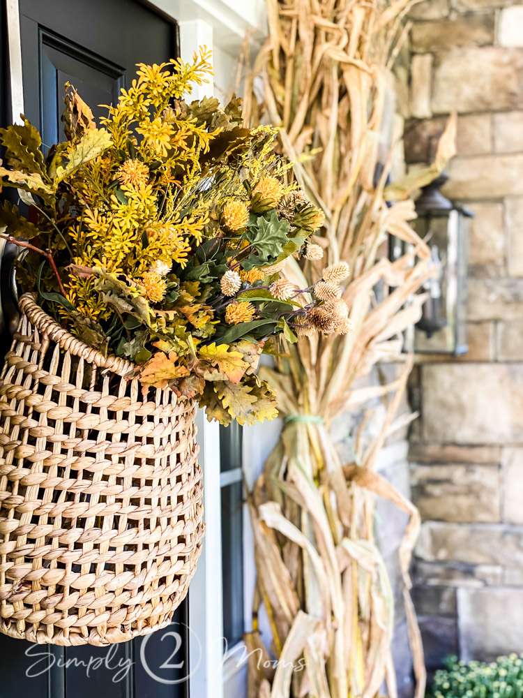 A fall door basket on a front door filled with faux fall flowers.
