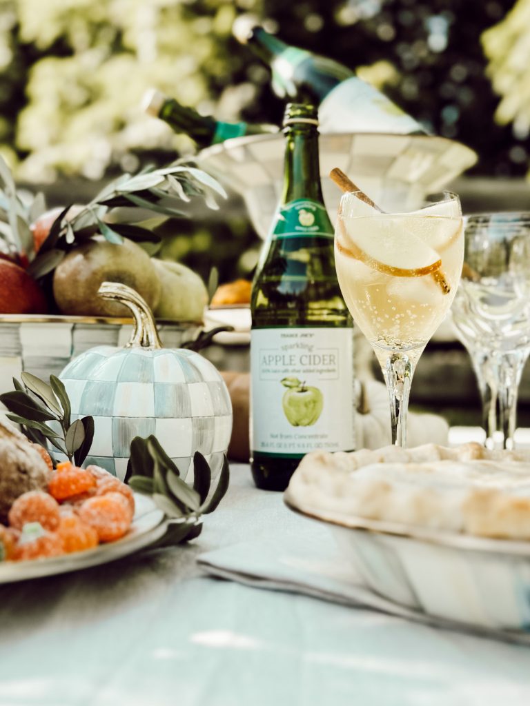 Create an autumn inspired tablescape with apple cider, apples, and pumpkins.