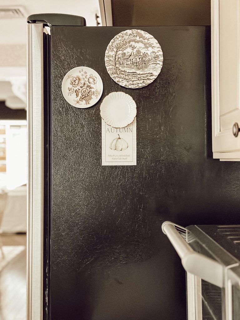 Fall artwork hung on the fridge by vintage plate magnets.