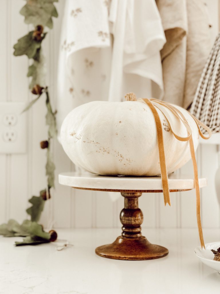 Natural fall decor in the kitchen with an acorn garland and white pumpkin.