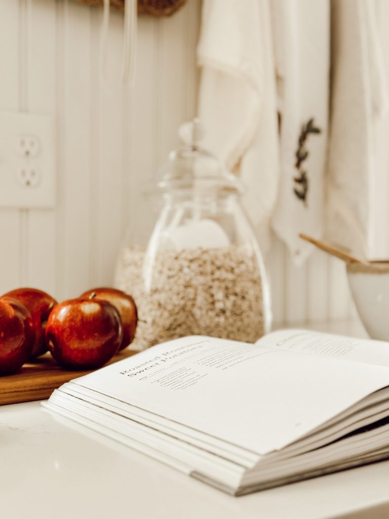 Apples and cookbook on kitchen countertop for fall farmhouse decor.