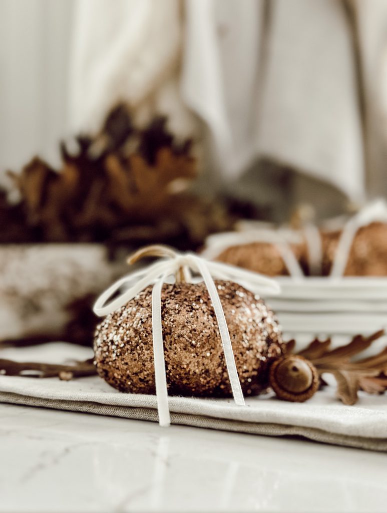 Create your own glitter pumpkins for fall decorations with glitter and small gourds.