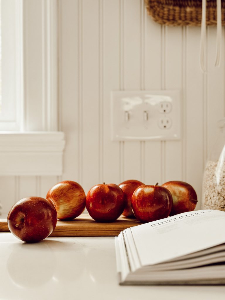 Fall farmhouse kitchen decor with apples, neutral colors, and seasonal accents.