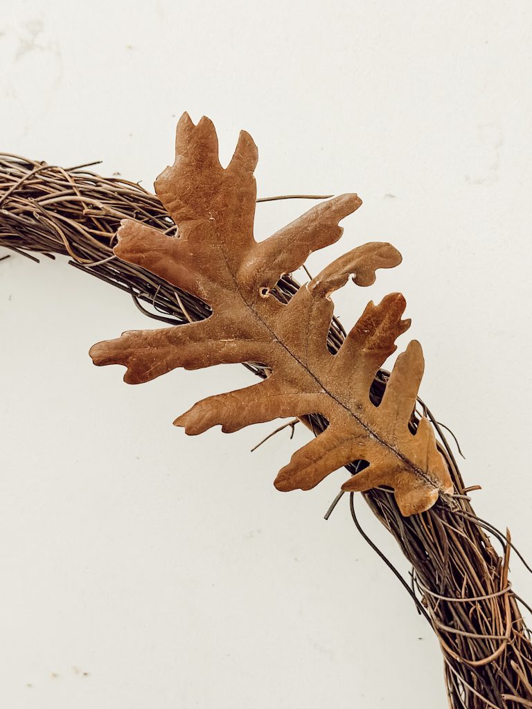 Rustic farmhouse wreath for fall with a grapevine wreath and dried leaves.