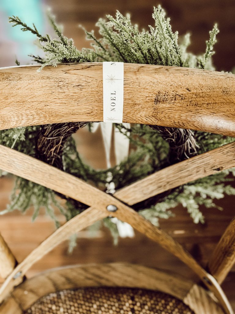 Back of chair with Christmas wreath hanging from white ribbon. 