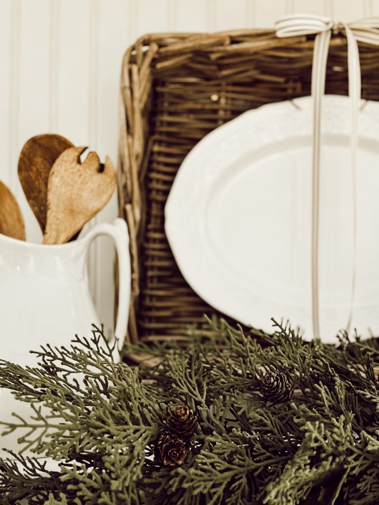 A woven basket for kitchen wall decor and a pitcher filled with wooden spoons.