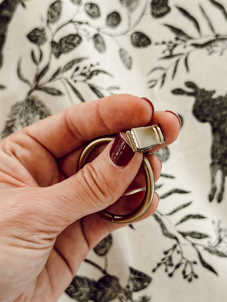 Clip rings for DIY curtains that are made from a green floral tablecloth. 