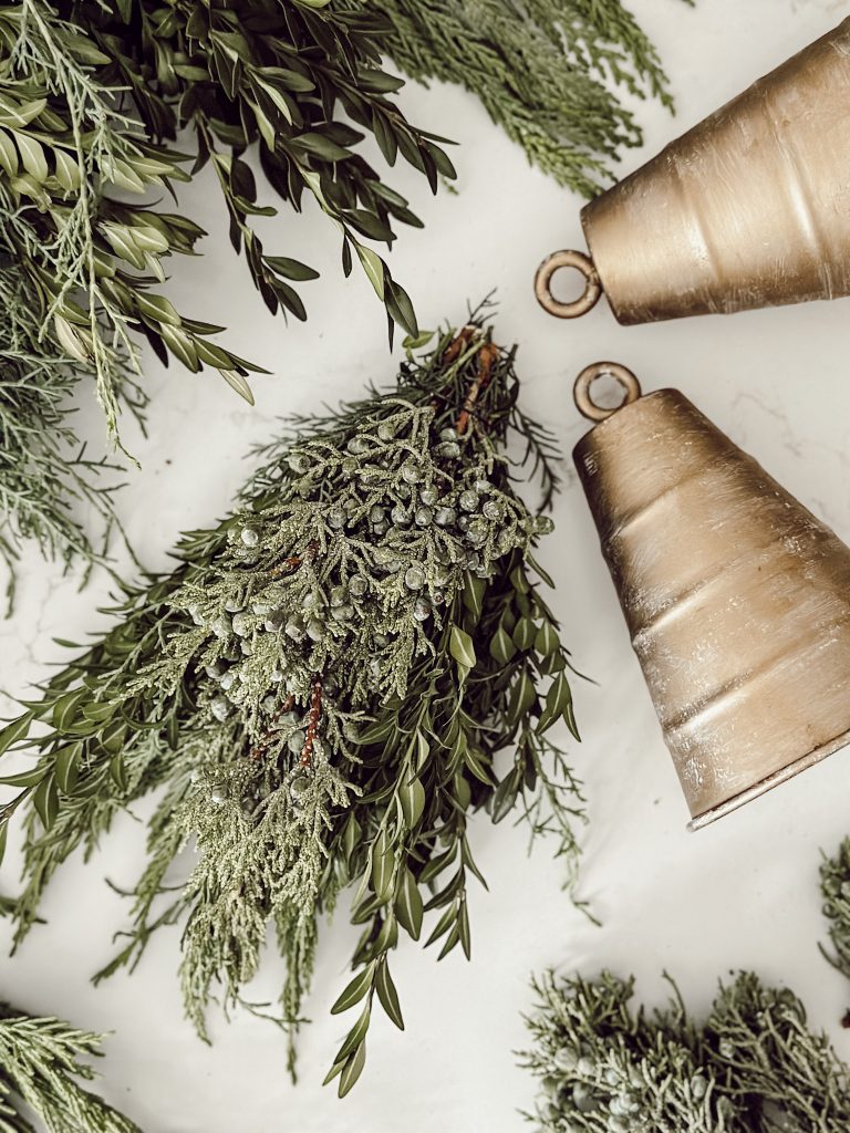 Fresh evergreens with gold bells for natural Christmas decorations.