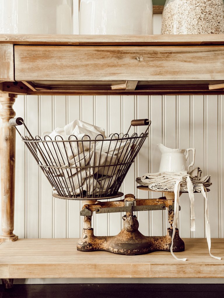Vintage scale with a basket of vintage linens on a wooden farmhouse table.