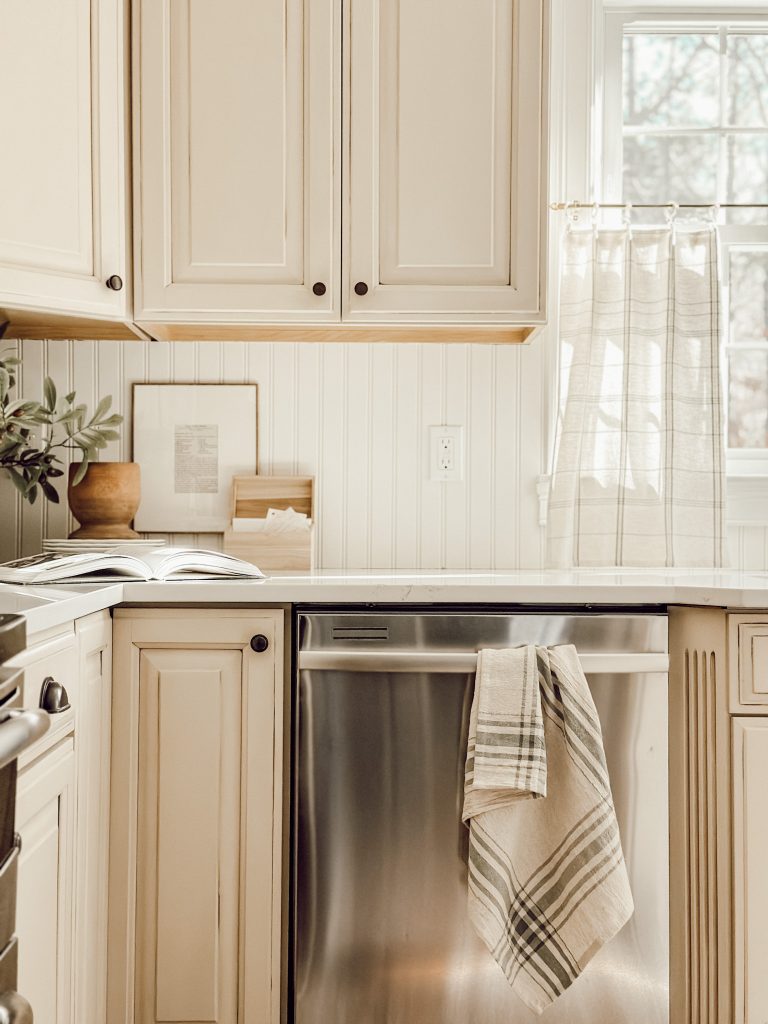 A neutral color palette in a cottagecore kitchen with a tea towel and curtains.