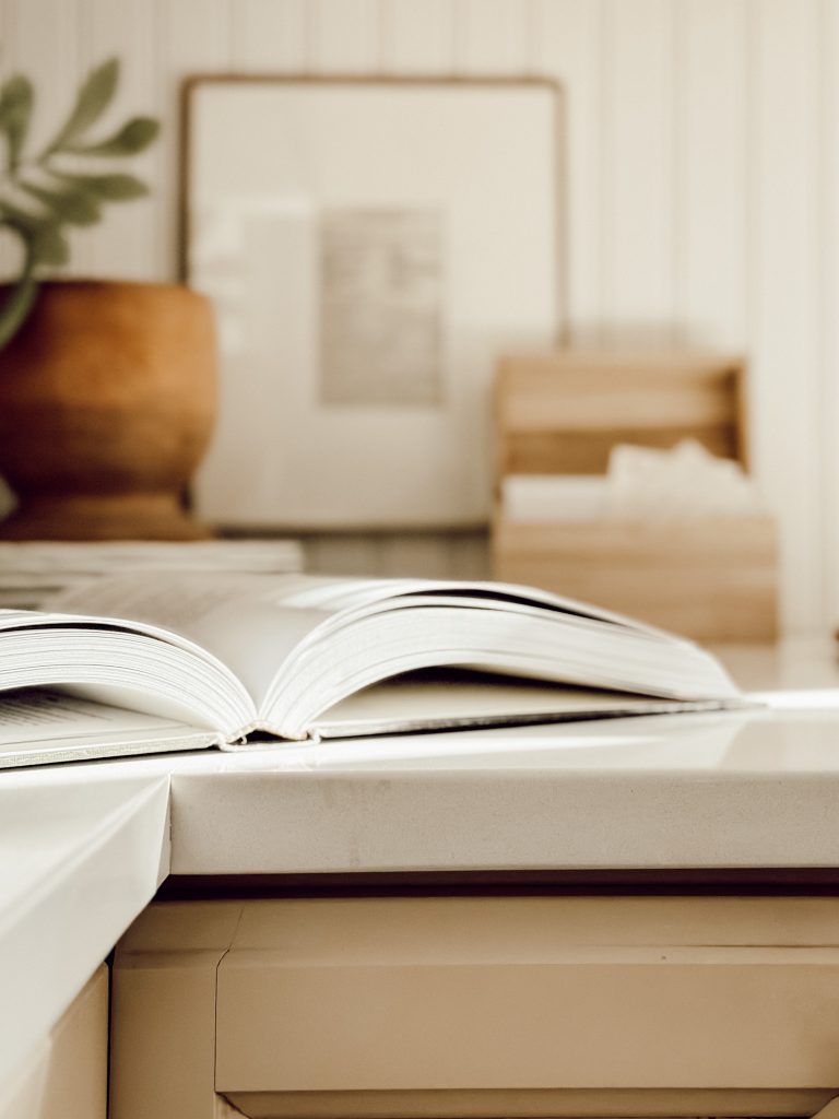 Recipes on display in the kitchen with a framed recipe card, recipe box, and cookbook.