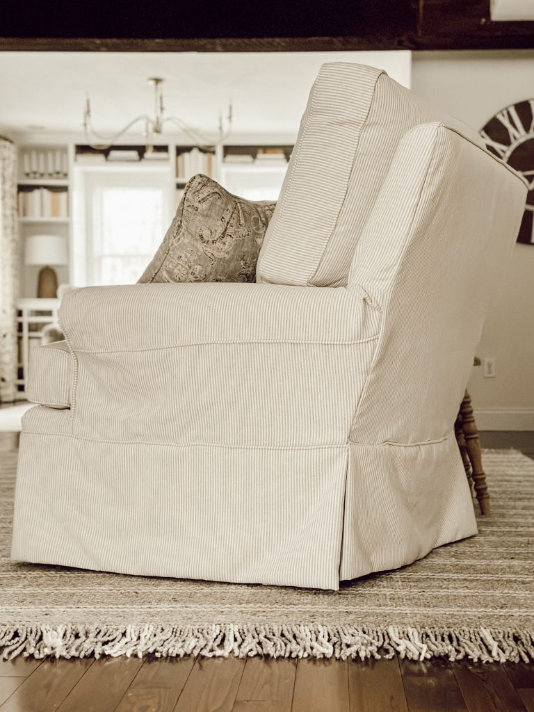 Striped slipcovered accent chair in living room for a cozy seating area.