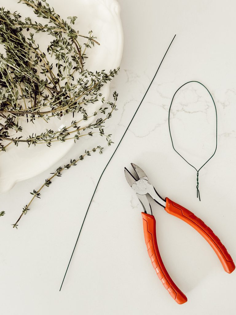 Florist wire shaped into a bunny ear that will be wrapped with fresh thyme sprigs.