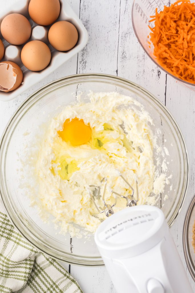 Hand mixer mixing eggs into carrot cake batter for keto cupcakes.