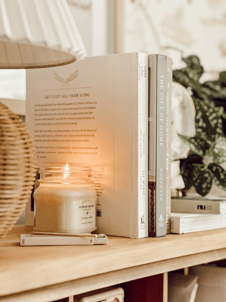 Desk found on Facebook Marketplace with a desk lamp, candle, books, and greenery.