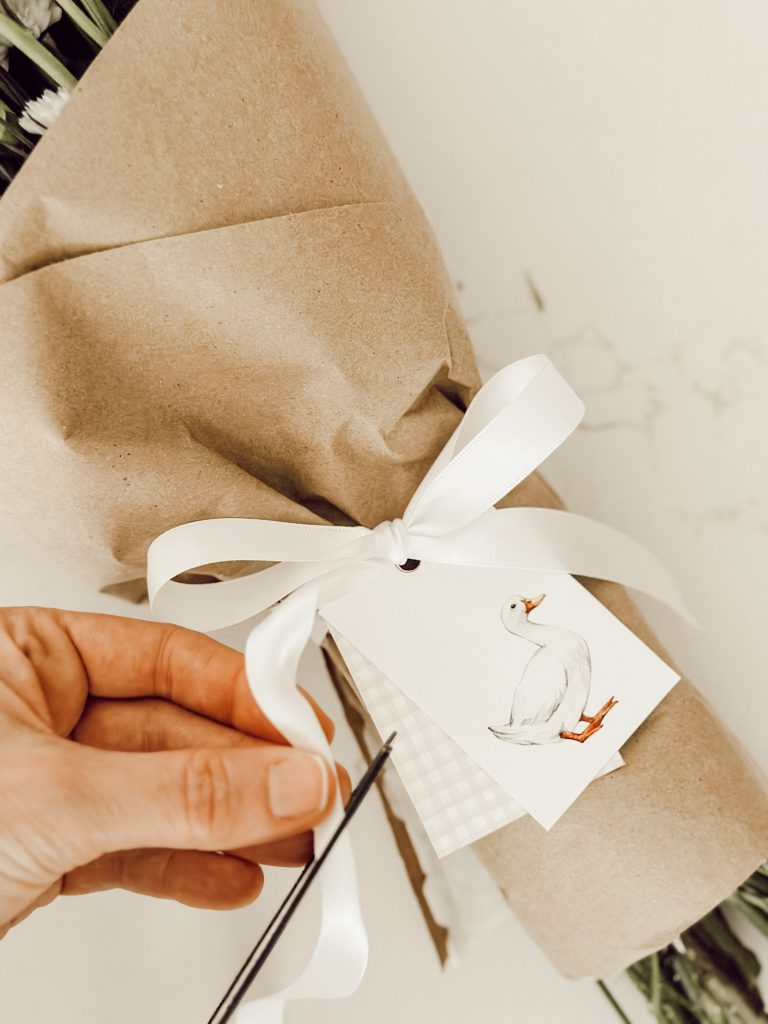 Using sharp scissors to trim the ends of the white satin ribbon.